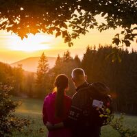 Zwei Rothaarsteig-Wanderer schauen in den Sonnenuntergang auf der Rothaarsteig-spur Sorper Panoramapfad