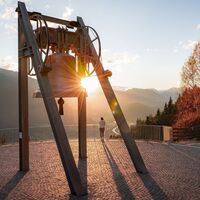 Friedensglocke im Herbst - Frau steht am Geländer und blickt ins Inntal beim Sonnenuntergang- Sonnenstern an der Glocke.jpg