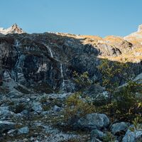 Alpine Bergwelt mit einem kleinen Bach und Wasserfall.