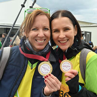 Glückliche Läuferinnen zeigen ihre Finisher Medaille
