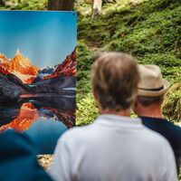 Besucher:innen betrachten eine farbenreiche Bergfotografie entlang des Kunstwanderwegs.