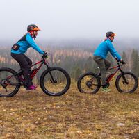 Zwei Personen beim Mountainbiken. Herbstlandschaft im Hintergrund.