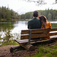 Möserer See im Frühling - Paar sitzt auf Bank und schaut auf den See Aufnahme von hinten (1).jpg