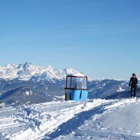 An der Gondel vorbei verläuft die Abfahrt vom Hochkeil auf den Knappensteig. Im Hintergrund das Dachsteinmassiv.