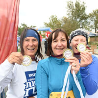 Glückliche Läuferinnen im Ziel zeigen ihre Finisher-Medaillen
