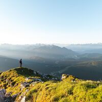 Wanderer auf der Gehrenspitze im Sonnenaufgang - Blick auf die Region Seefeld - Panoramaaufnahme.jpg