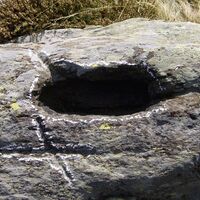Ein kleiner Felsen mit einer eingravierten Mulde, Rinnen und einem Kreuz, Alpe Avaiscia.