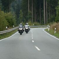 Motorradfahrer auf einer Landstraße im Waldgebiet