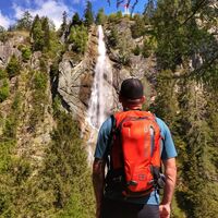 Wanderer mit Rucksack vor dem Steiner Wasserfall in der Proßeggklamm
