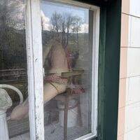 Nackte Frau im Fenster, nur notdürftig mit rotem Wollschal bedeckt..