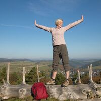 Frau auf Baumstamm mit toller Aussicht
