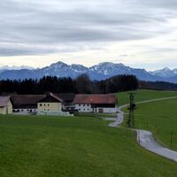 Auf einem sanften Höhenrücken verläuft der Rückweg an den Häusern von Schlipfing vorbei.