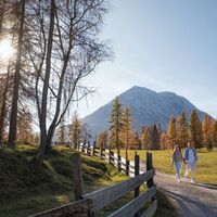 Herbstwanderung am Oberen Wiesenweg_junges Paar läuft auf breitem Weg_Hohe Munde im Hintergrund.jpg