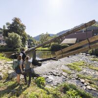 Drei Personen stehen an der Kinzig in Schiltach neben einem Gamber