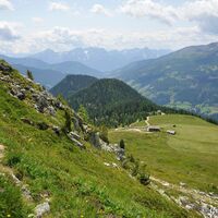 Am Grat entlang bummeln wir über bunte Blumenwiesen zum Gasthaus Glocknerblick, unten im Tal schon sichtbar.