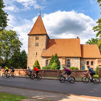 Rennradgruppe vor der St. Bartholomäus-Kirche in Kirchwalsede