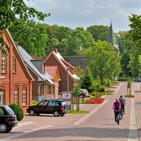 Radfahrer fahren in Richtung der Gangolf-Kirche in Oerel