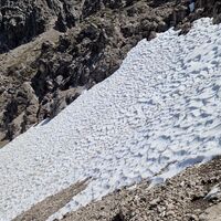 Um diese Zeit noch Schnee im Nordhang, das Schneefeld muss gequert werden, dahinter sieht man noch die Kletterstellen über die der Weg hinuntergeht (Rückblick Richtung Osten).