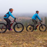 Zwei Personen beim Mountainbiken. Im Hintergrund eine herbstliche Landschaft.