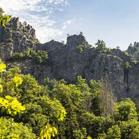Blick durch Bäumen auf den Falkenstein mit Gipfelkreuz im Schlüchttal