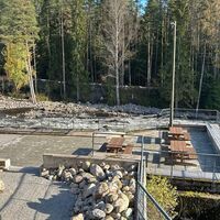 Erholungsgebiet am Flussufer, im Hintergrund Wasserfall und Brücke