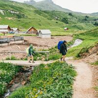 Der Weg führt vorbei an Blumenwiesen und Alphütten.