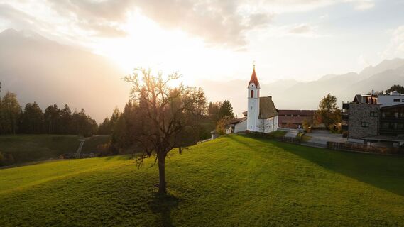 Drohnenaufnahme Mösern im Herbst_Kirche bei Sonnenuntergang.jpg