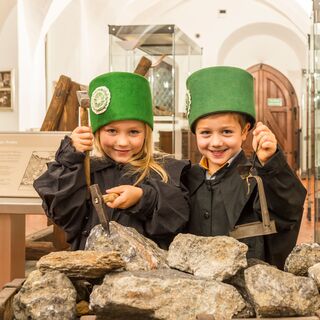 zwei Kinder in Bergbauuniform, an einem Erzhunt in der Bergbauausstellung des Stadt- und Bergbaumuseums Freiberg stehend