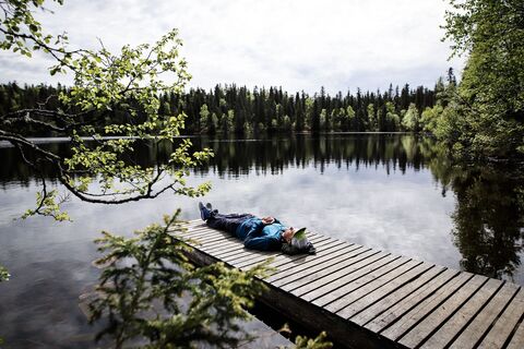 Wanderer entspannt sich auf dem Steg des Valtavaaranlampi in Ruka