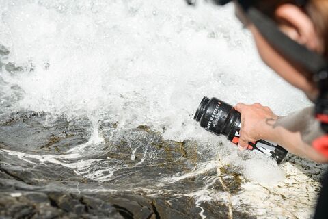 Radfahrer füllt seine Flasche im Fluss.