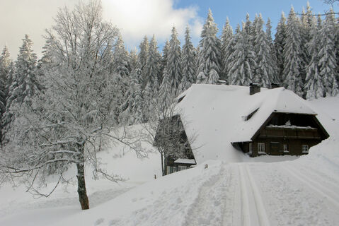 Verschneiter Bauernhof mit Loipe