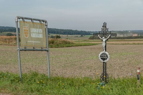 Wegkreuz, im Hintergrund Staub vom Nordring