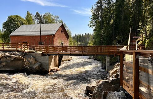 Brücke über den Wildwasserfluss, im Hintergrund ein altes Backsteinkraftwerk