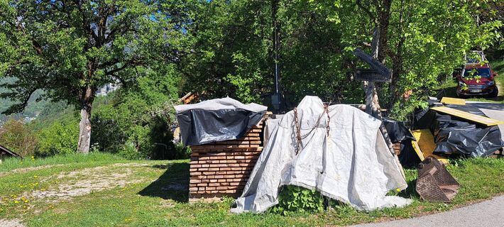 Der Wanderweg geht hier links am Holzstapel vorbei weiter