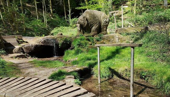 Wassertretbecken mit Bärenskulptur unterhalb des Naturdenkmals Bärenhöhle