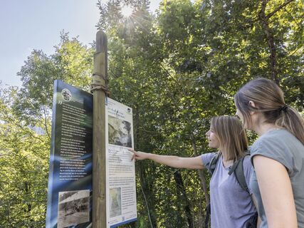 Zwei Wanderinnen schauen sich eine Thementafel des Flößerpfads an