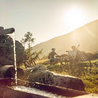 Mountainbiker machen eine Pause vor einem Brunnen, Lötschental, Bietschhorn Bike
