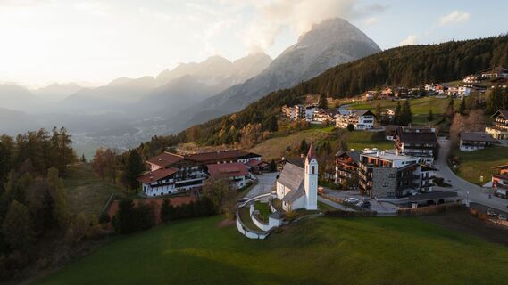 Drohnenaufnahme Mösern im Herbst_Aufnahme bei Sonnenuntergang_Kirche und Hohe Munde.jpg