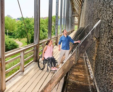 Ein Mann und eine Frau im Rollstuhl besuchen das Gradierwerk in Bad Dürkheim