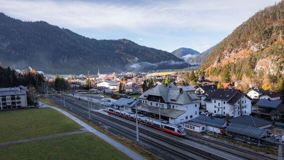 Drohnenaufnahme Bahnhof Scharnitz im Herbst bei Morgenlicht Zug am Bahnsteig.jpg