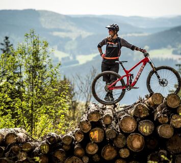 Bikerin mit Mountainbike auf Holzstapel