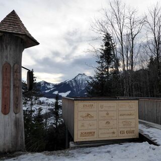 Krispl mit Ausblick: auf den markanten Schmittenstein und vor der Plattform auf den Brauch der Totenbretter, der an die Verstorbenen erinnert.