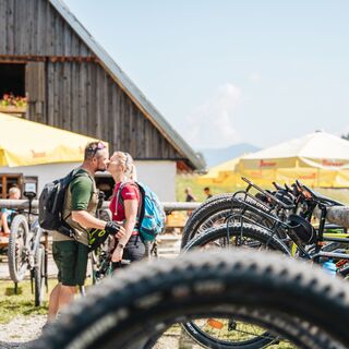 zwei Radfahrer die sich auf der Ebenforstalm im Hintergrund küssen.