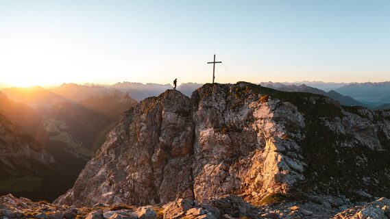 Wanderer auf der Gehrenspitze ueber Leutasch im Sonnenaufgang - Panoramaaufnahme.jpg