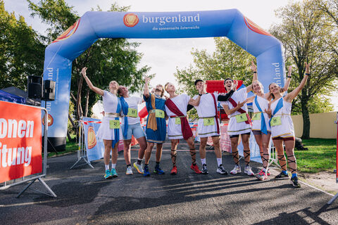 Kostümierte Marathonläufer:innen vor dem Torbogen im Start-/Zielbereich