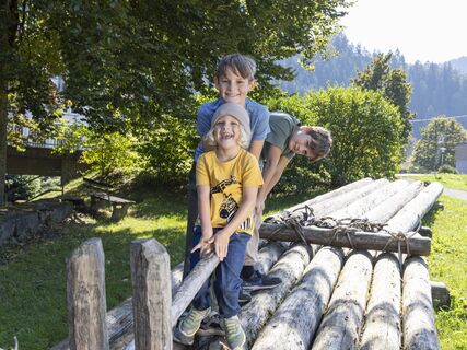 Drei Kinder sitzen auf einem Holzfloß in der Ortsmitte Schenkenzell