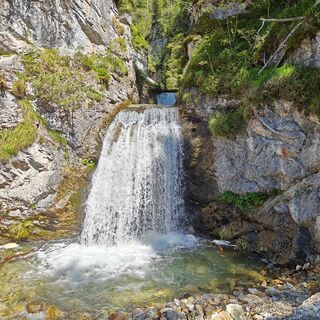 Moosbewachsene Felsen säumen den versteckten Wasserfall in Salzburgs kleinster Gemeinde.